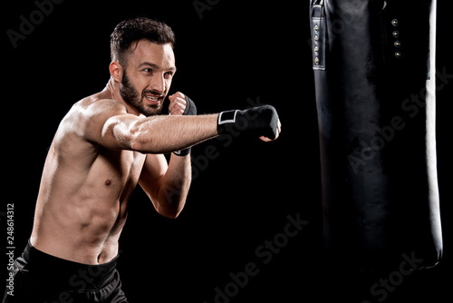 handsome bearded man exercising with punching bag isolated on black © LIGHTFIELD STUDIOS