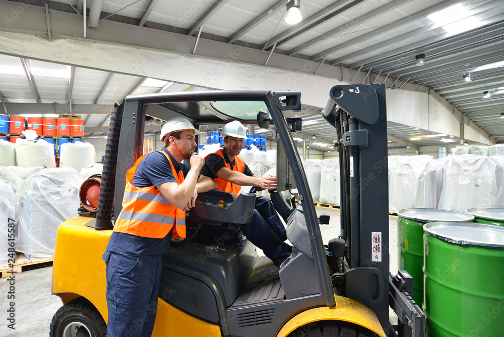 Arbeiter in der Logistik im Warenlager // Discussion of workers in a warehouse at a forklift truck on the subject of work safety Arbeiter in der Logistik im Warenlager // Discussion of workers in a warehouse at a forklift truck on the subject of work safety