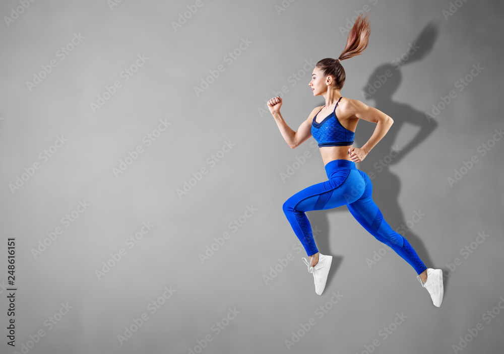 Fototapeta premium Young woman runner in blue sportswear jump in the air.