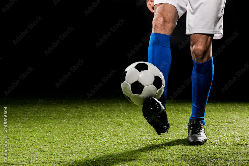 cropped view of man playing with ball on grass isolated on black cropped view of man playing with ball on grass isolated on black