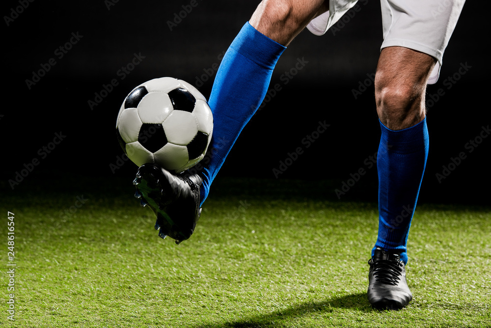 cropped view of sportsman playing with ball on grass isolated on black