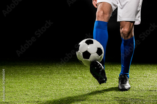 cropped view of man playing with ball on grass isolated on black