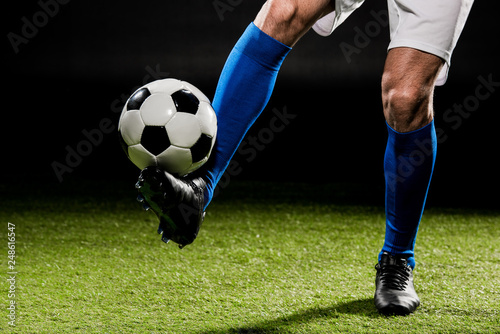 cropped view of sportsman playing with ball on grass isolated on black © LIGHTFIELD STUDIOS