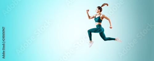 Young woman runner in blue sportswear jump in the air.