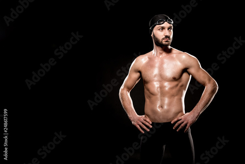 muscular swimmer standing in swimming cap and swim goggles isolated on black © LIGHTFIELD STUDIOS