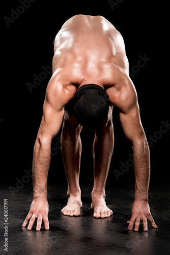 muscular man standing in start position on black background