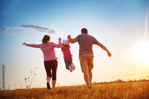 girl with mother and father holding hands on the nature