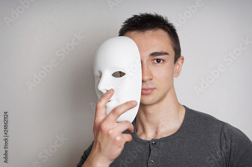 Obraz na plátně young man taking off plain white mask revealing face