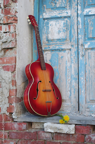 Acoustic old guitar against the background of blue shutters © yrafoto