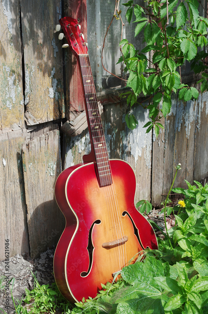 Acoustic old guitar on the background of the old wall