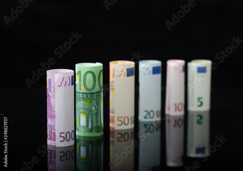 European paper money in rolls, on black background.