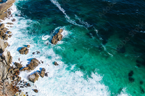 Background texture of a rocky shore and blue and turquoise water and waves of the Atlantic Ocean at the Cape of Good Hope in South Africa