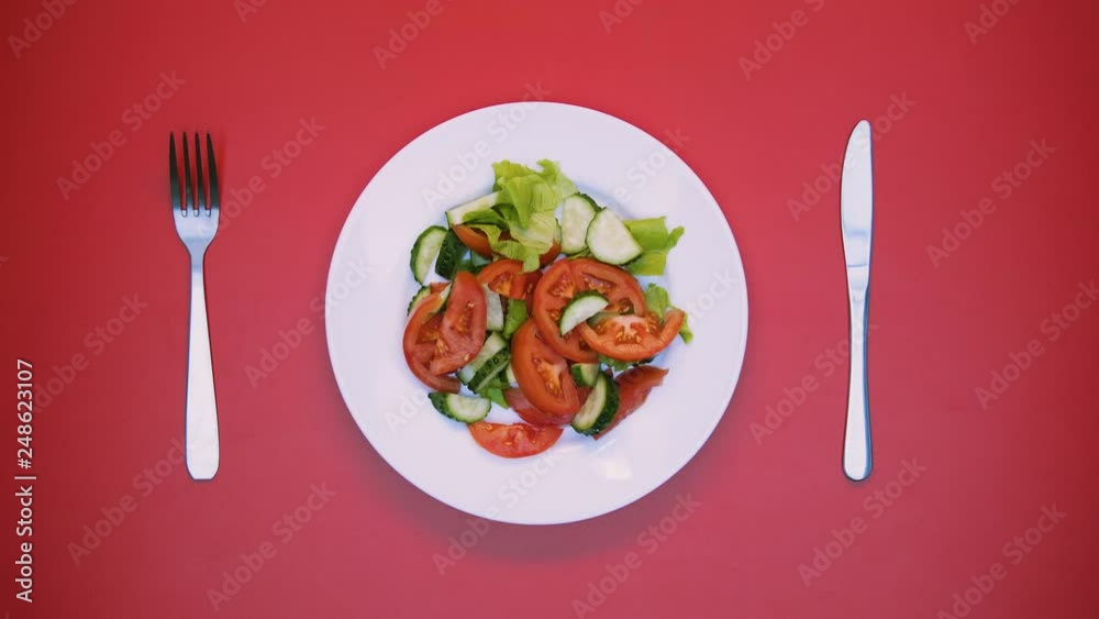 White table with salad and cutlery rotating on bright background, table setting White table with salad and cutlery rotating on bright background, table setting
