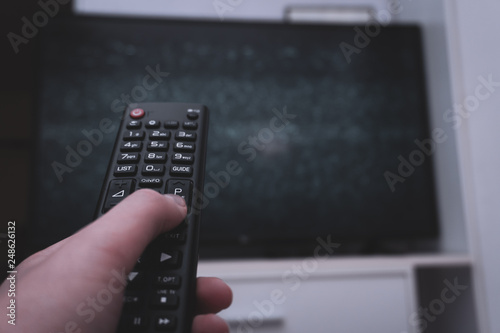 Female holding TV remote control in front of TV. Couch potatoe. Point of view shot.