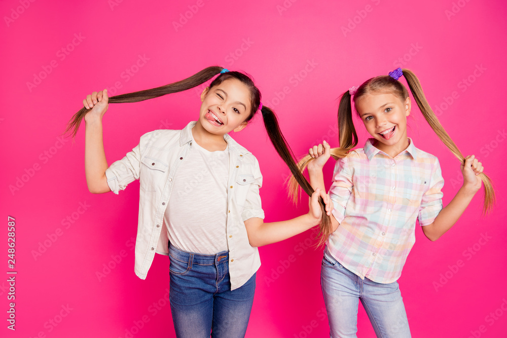 Close up photo two pretty little age girls holiday having fun childish glad tongue out mouth blinking playing wearing casual jeans denim checkered plaid shirts isolated rose vivid vibrant background Close up photo two pretty little age girls holiday having fun childish glad tongue out mouth blinking playing wearing casual jeans denim checkered plaid shirts isolated rose vivid vibrant background