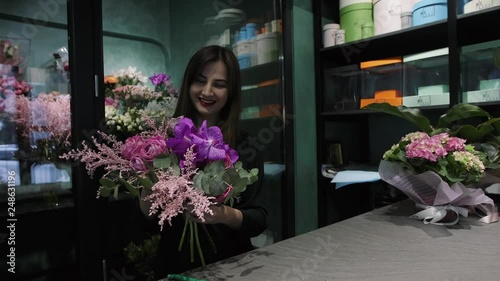 Professional woman florist makes the bouquet from pink flowers tulips, roses, orchids and solidago.