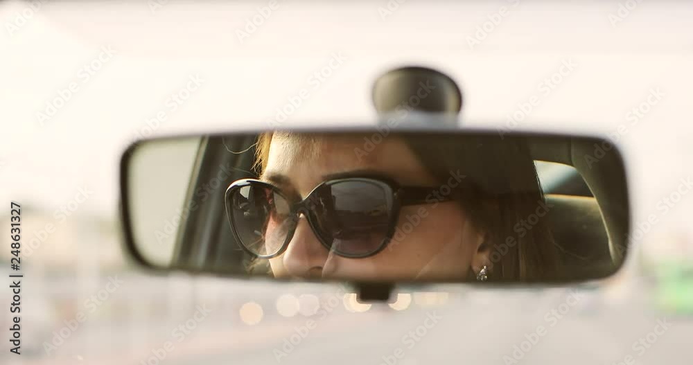 The woman in sunglasses is driving a car. The woman in sunglasses is driving a car.