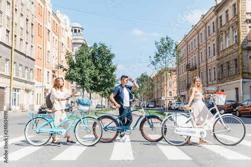 Best friends with retro bicycles cross the road, enjoying carefree time with friends, safe road crossing, urban transport, joyful time/ summertime, leisure and lifestyle concept.
