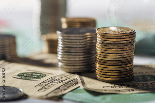 selective focus of coins stacks on dollars banknotes with blurred background