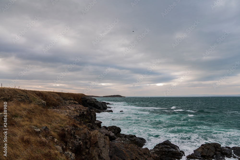 sea ​​scenery in dramatic weather in the blue hour. a landscape with dramatic clouds and stormy water that breaks down on the shore and the rocks.