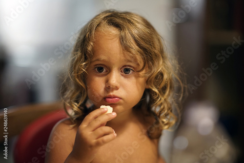 Little girl eats a piece of cheese thoughtfully
