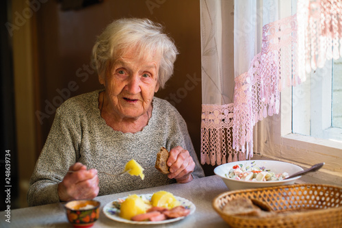 An elderly woman portrait dines in his home. photo