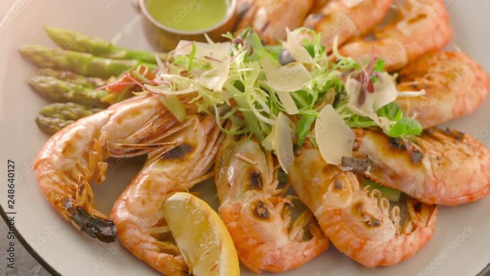 Top view of roasted shrimps served with asparagus and lemon on white plate Top view of roasted shrimps served with asparagus and lemon on white plate