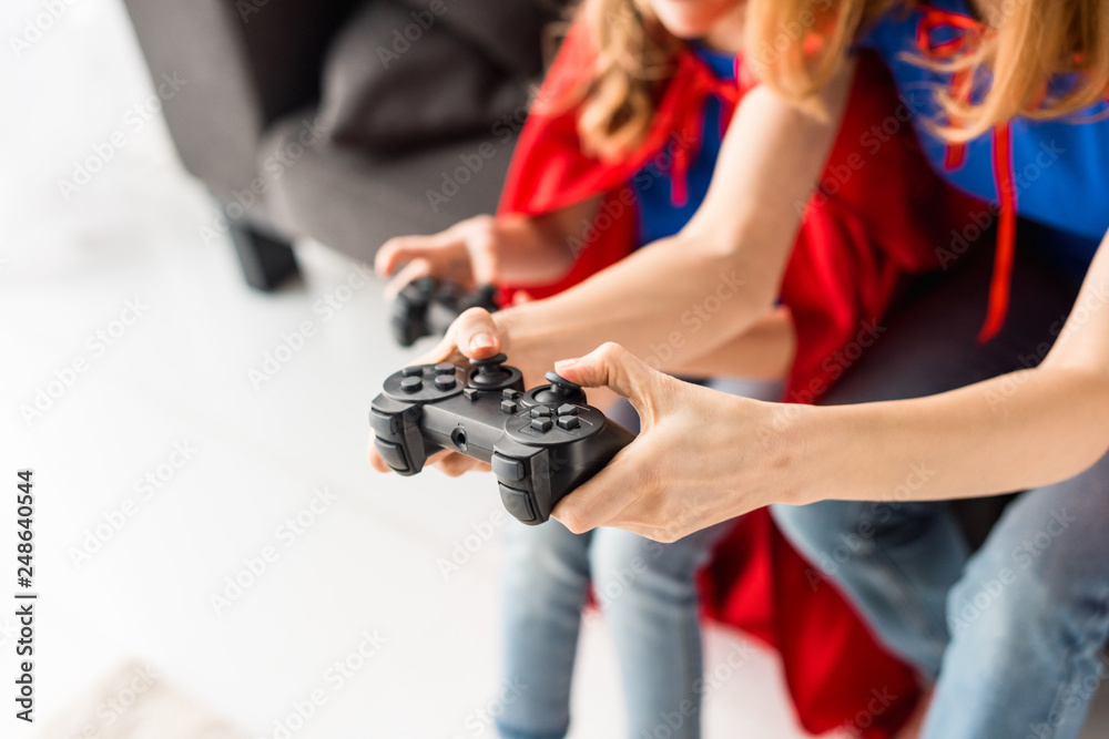 Partial view of woman and kid playing video game at home