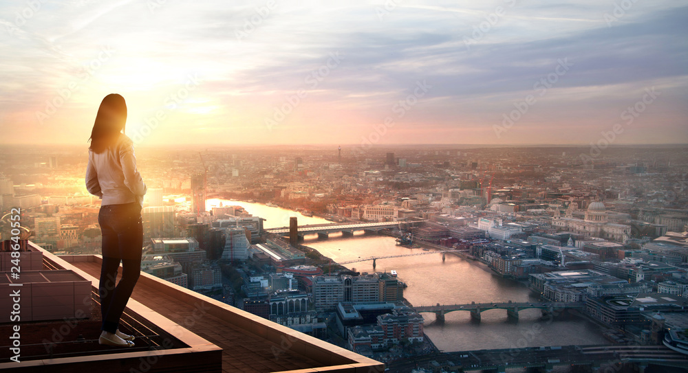 Fototapeta premium Young woman looking at the City of London at sunset. Planning the future, life and joy concept.