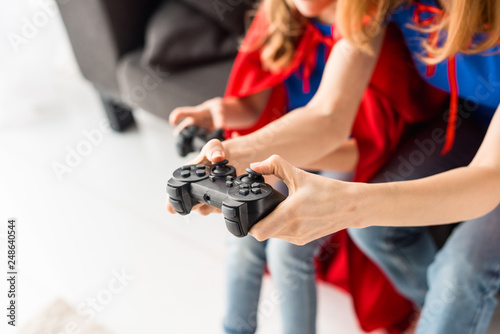 Partial view of woman and kid playing video game at home