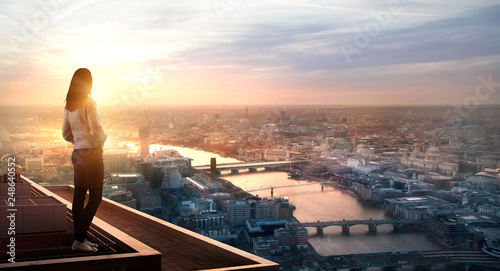 Young woman looking at the City of London at sunset. Planning the future, life and joy concept. photo