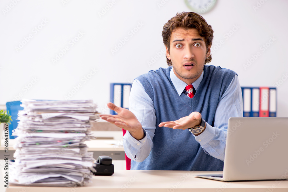 Young handsome employee unhappy with excessive work Young handsome employee unhappy with excessive work
