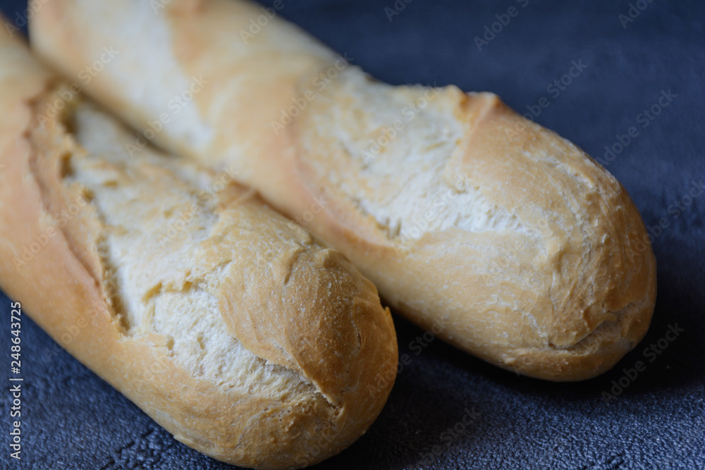 Macro view of freshly baked crunchy baguette bread on dark background. Closeup of crust of bread food background. Natural lighting 