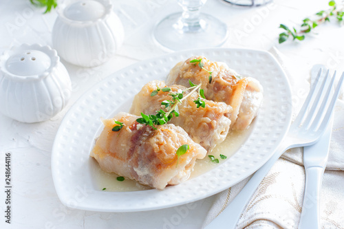 Chicken rolls with bacon and cheese on a white table, horizontal