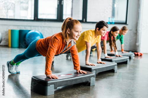 Children doing plank exercise with step platforms photo