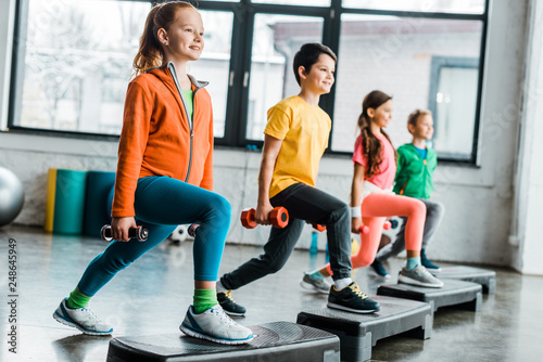 Preteen kids training with dumbbells and step platforms