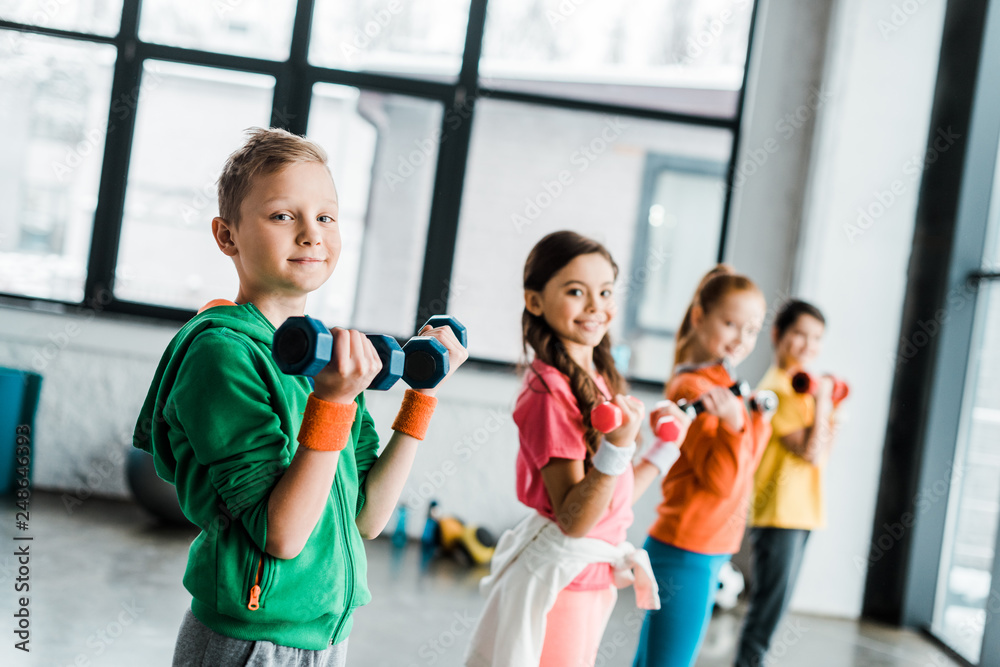 Cute children with dumbbells looking at camera