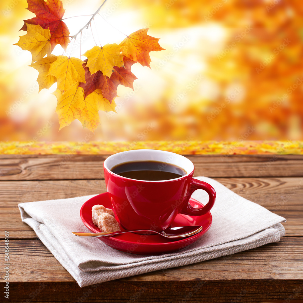 Red cup of tasty coffee on napkin, on wooden table. Autumn background Red cup of tasty coffee on napkin, on wooden table. Autumn background