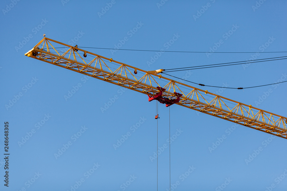 The yellow crane in the daylight. Construction technology. Modern construction crane for lifting building materials The yellow crane in the daylight. Construction technology. Modern construction crane for lifting building materials