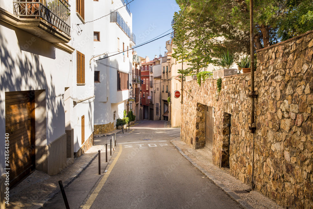 Streets and buildings in the city of Tossa de Mar, Spain. Narrow passages between houses. Shops and restaurants in the center.