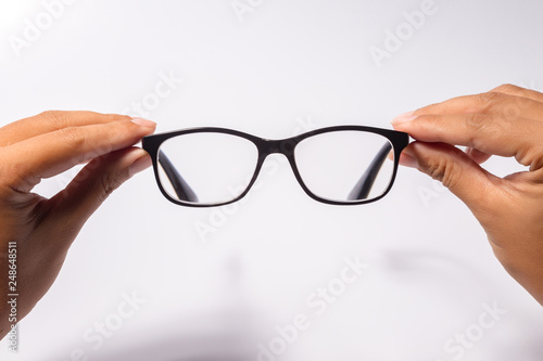 Man holding the black eye glasses spectacles with shiny black frame isolated on white
