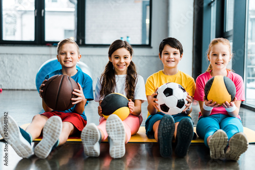 Fototapeta Naklejka Na Ścianę i Meble -  Preteen kids sitting on fitness mat with balls