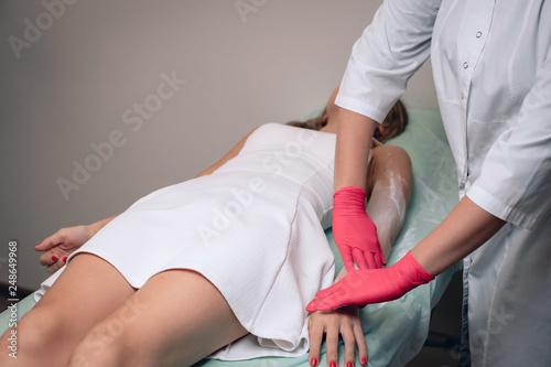 Beautician removes hair from a woman's hand. Sugaring. Hair removal with a special sugar paste has many advantages over wax depilation. Close-up.