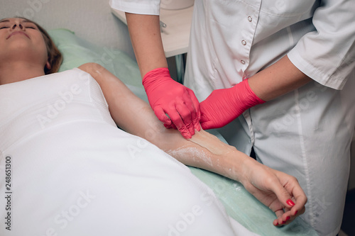 Beautician removes hair from a woman's hand. Sugaring. Hair removal with a special sugar paste has many advantages over wax depilation.. © Semachkovsky 