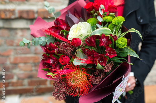 Bouquet of colorful flowers in hands. Alstromeriya, leucospermum, rose, chrysanthemum, dragon tree, eucalyptus photo