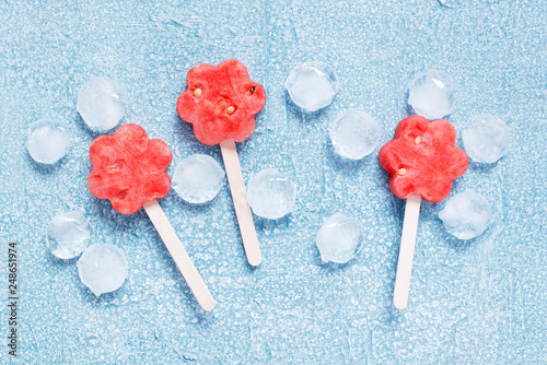 Popslices of fresh watermelon and ice on blue