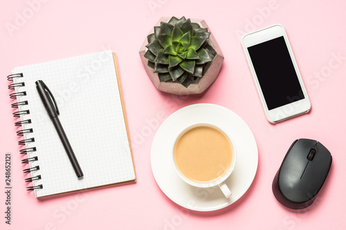 Freelance workplace with notepad  coffee cup  succulent and mouse on pink