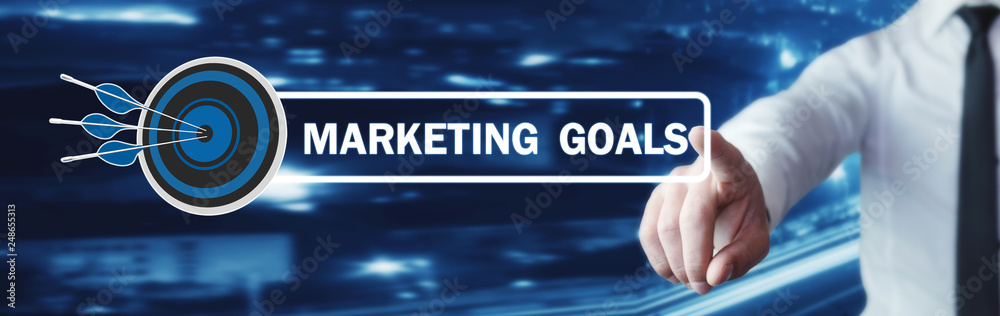 Hand touching on Marketing Goals text with a target dart. Hand touching on Marketing Goals text with a target dart.