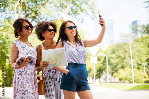 tourism, travel and technology concept - happy women with city guide and map taking selfie by smartphone in summer park © Syda Productions
