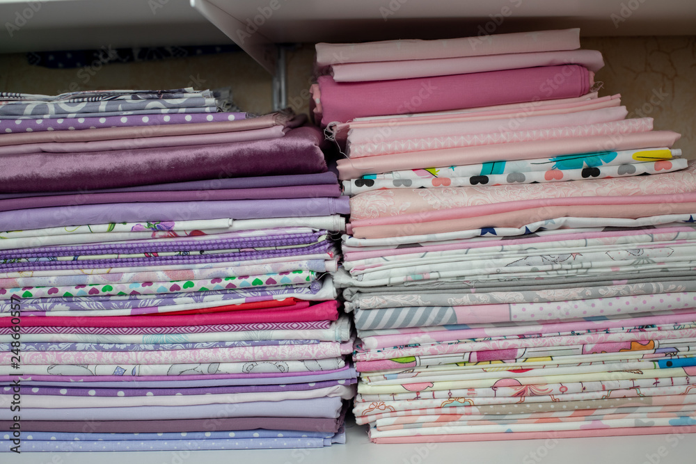 lots of bundles of different verities of new fabric in many color collections kept on the shelf of a local store in Asia